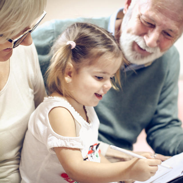 Grandparents With Young Grandaughter Colouring In